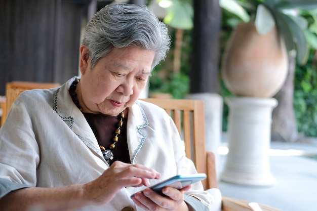 Senior vrouw met behulp van mobiele slimme telefoon. oudere vrouwelijke bedrijf mobiele telefoon