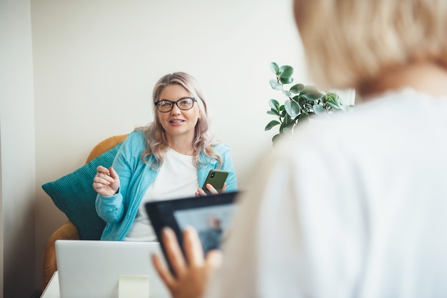 Senior vrouw met een bijeenkomst thuis tijdens het gebruik van een laptop en bril dragen