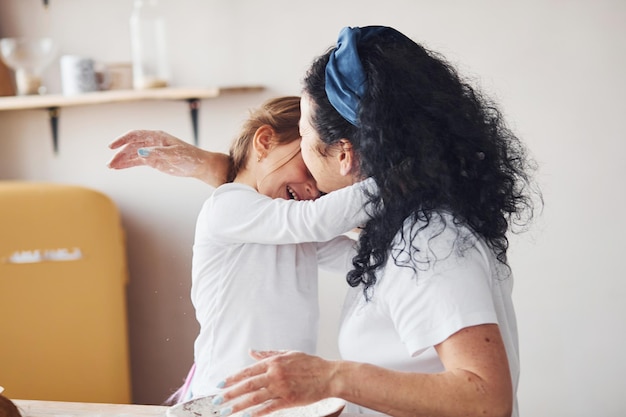 Senior vrouw met haar kleindochter die voedsel bereidt met bloem op de keuken