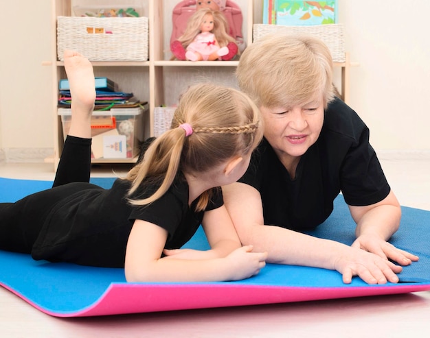 Senior vrouw met kleindochter liggend op fitness mat ontspannen en praten na training of training