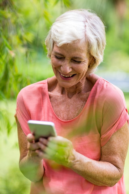 Senior vrouw met telefoon in tuin