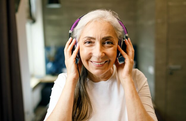 Senior vrouw met wit haar in koptelefoon luisteren naar haar favoriete muziek