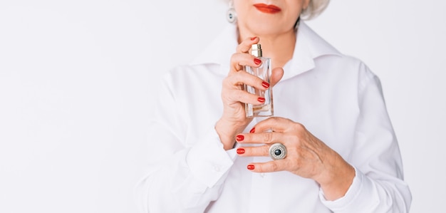 Senior vrouw mode-stijl. Parfum trends. Fles dure geur in vrouwelijke handen.