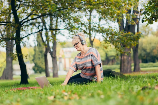 Senior vrouw ontspannen in het park met een laptop