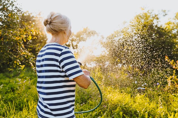 Senior vrouw planten in de tuin water geven