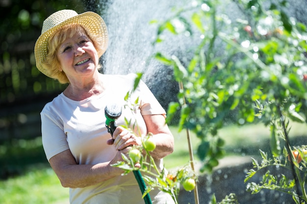 Senior vrouw planten water geven met een slang