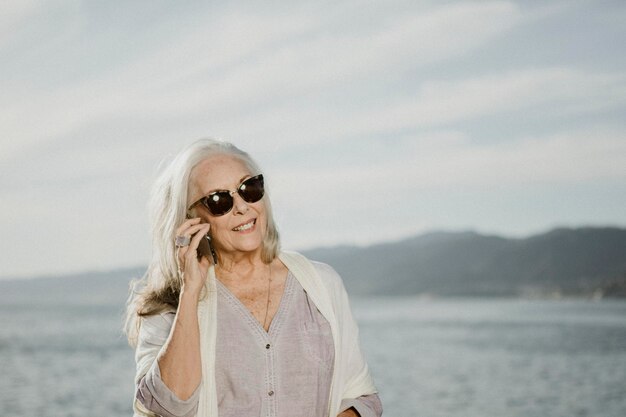 Senior vrouw praten aan de telefoon aan zee