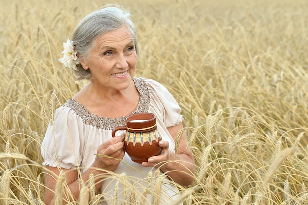 Senior vrouw rust op zomer veld met melk in kruik