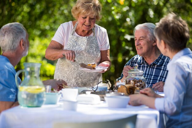 Senior vrouw serveert ontbijt in de tuin