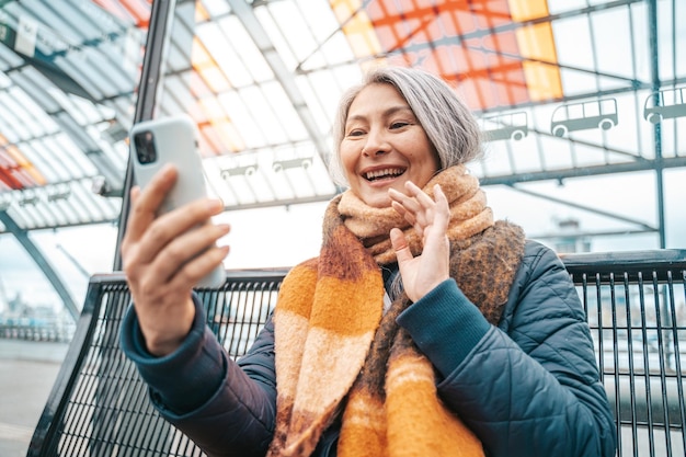 Senior vrouw spreekt met vrienden via smartphone