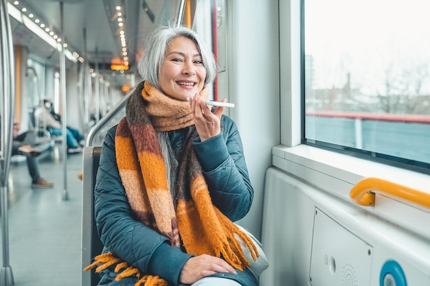 Senior vrouw stuurt bericht met een mobiele telefoon in een trein