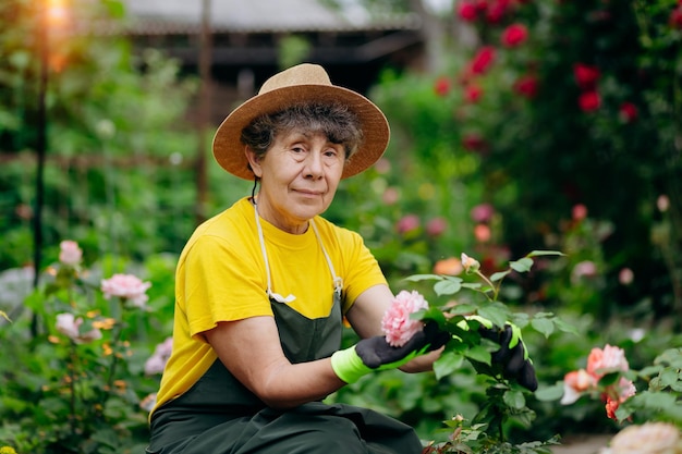 Senior vrouw tuinman in een hoed die in haar tuin werkt met uitrustingsstukken Het concept van tuinieren, groeien en zorgen voor bloemen en planten