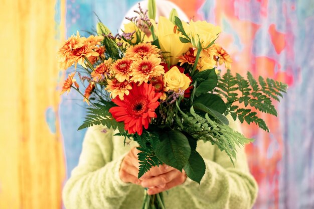 Senior vrouw verborgen door een boeket bloemen geïsoleerd op kleurrijke achtergrond Valentijnsdag Vrouwendag verjaardagsfeestje vakantie