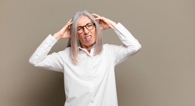 Senior vrouw voelt zich gefrustreerd en geïrriteerd, ziek en moe van mislukking, beu met saaie, saaie taken