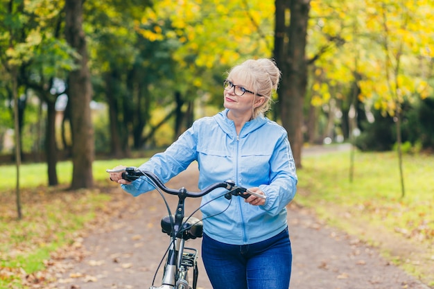 senior vrouw wandelen in het park met een fiets