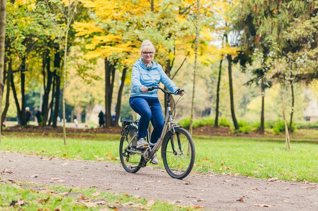 senior vrouw wandelen in het park met een fiets