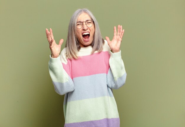 Senior vrouw woedend schreeuwend, gestrest en geïrriteerd met handen in de lucht en zei waarom ik