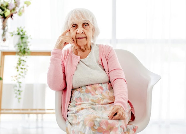 Senior vrouw zitten en kijken naar de camera. gepensioneerde bejaarde portret thuis