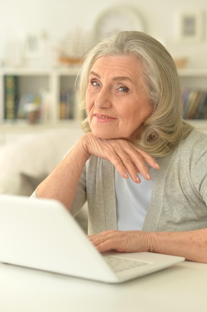 senior vrouw zittend aan tafel met laptop