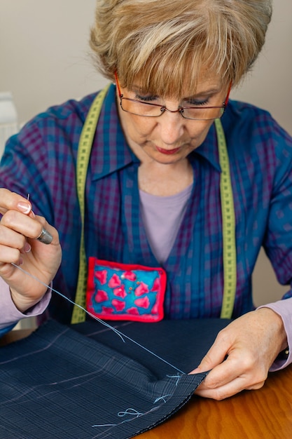 Foto senior vrouwelijke naaister naaidoek om een kledingstuk te maken in haar atelier