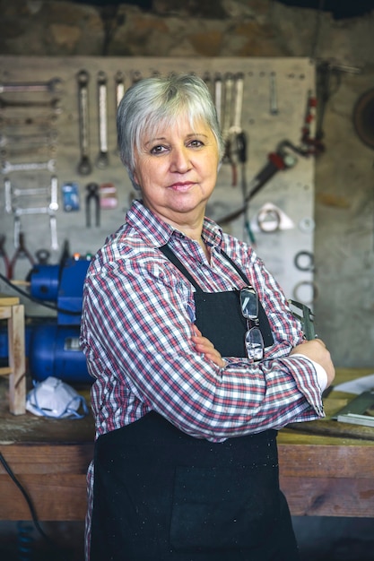 Foto senior vrouwelijke timmerman poseren met gekruiste armen in zijn atelier