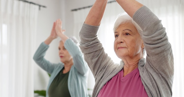 Senior vrouwen yoga en les met vrienden en bejaardentehuis verzorger met een glimlach Fitness ouderen groep en training voor welzijn en gezondheid met verpleegster in een woonkamer met oefening om te ontspannen