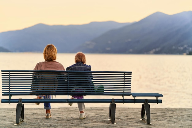 Senior vrouwen zitten op de bank aan de dijk van Ascona aan het Lago Maggiore, Ticino kanton Zwitsers