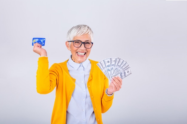 Senior woma holding money dollar bills and credit card in hand.