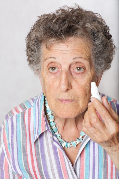 Senior woman between 70 and 80 years old and eye drops