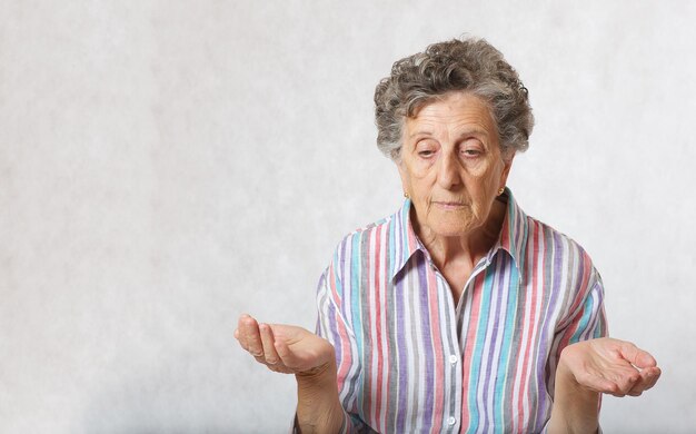 Foto la donna anziana tra i 70 e gli 80 anni sta pensando a qualcosa. sfondo grigio