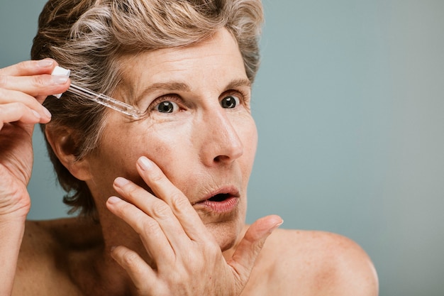 Senior woman applying moisturizer on her eye wrinkles