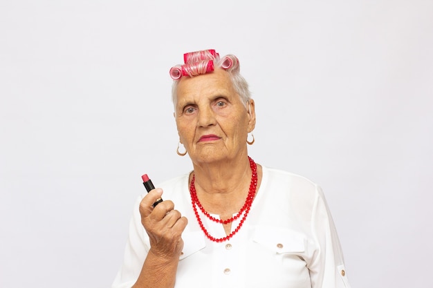 Senior woman applying pink lipstick