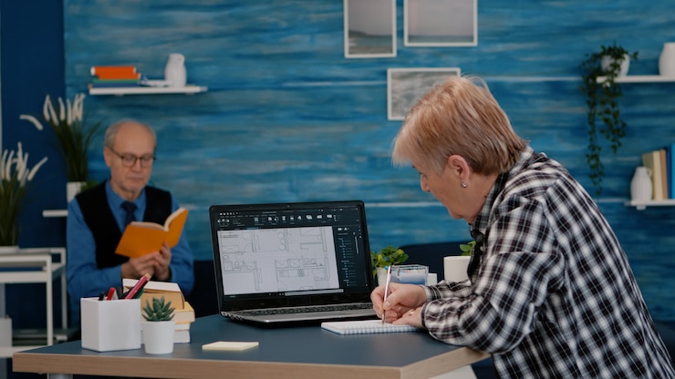 Photo senior woman architect analysing digital prototype with plans from laptop