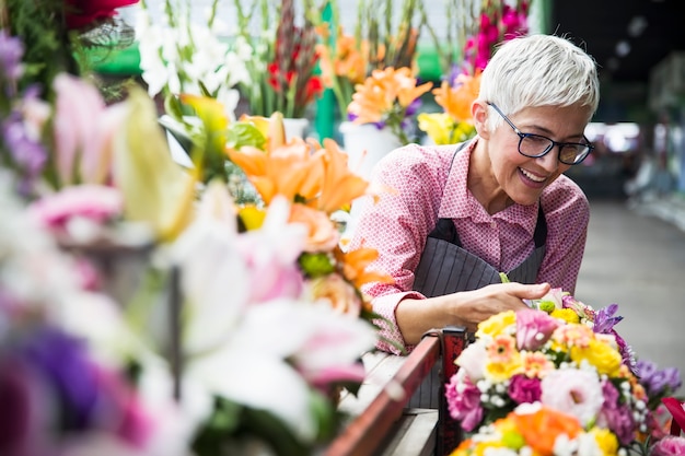 Senior woman arranges flowers on local flower market