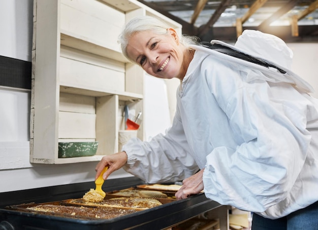 Foto donna anziana apicoltura e miele durante il processo di produzione per l'estrazione e la disopercolatura dell'apicoltura mentre si trova in un'officina o in una fabbrica per piccole imprese biologiche ritratto di agricoltore a nido d'ape che lavora