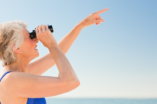 Uccello senior della donna che guarda in spiaggia