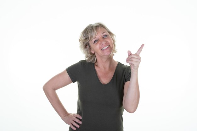 Senior woman blonde middle aged pointing fingers hand up copy space on white background