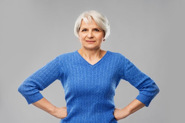 Photo senior woman in blue sweater hands on hips