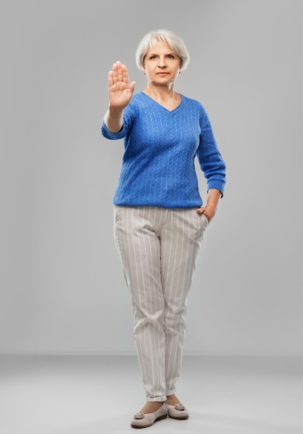 Photo senior woman in blue sweater making stop gesture