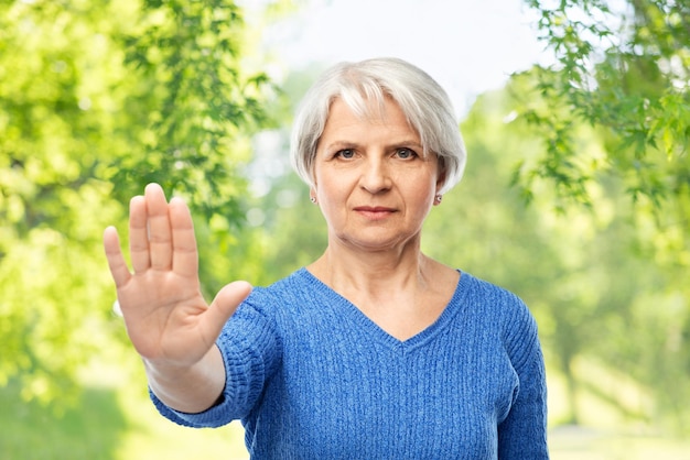 Foto donna anziana in maglione blu che fa il gesto di fermarsi