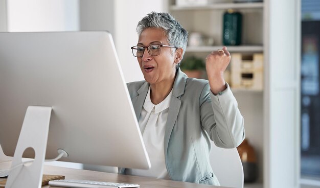 Senior woman call center and celebration for winning sale or promotion in telemarketing at the office desk Happy elderly female consultant or agent celebrating win bonus or victory by computer