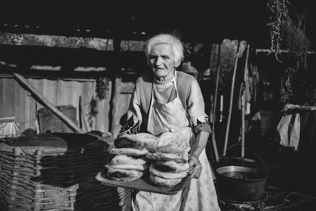 Foto donna anziana che porta un vassoio di pane al forno