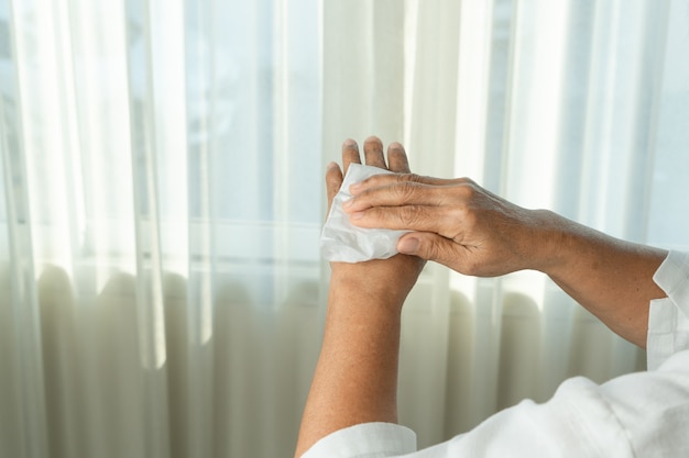 Foto donna anziana che si pulisce le mani con carta velina bianca. isolato su sfondi bianchi