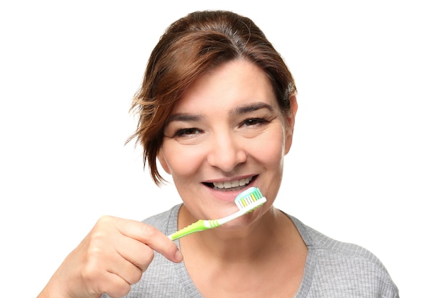 Senior woman cleaning teeth on white