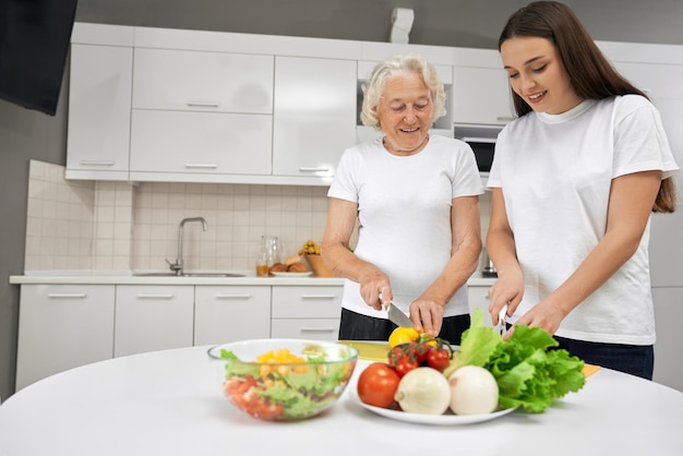 Senior woman cooking salad with granddaughter
