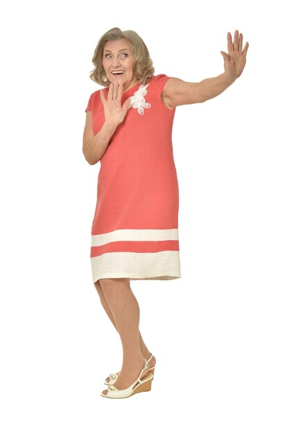 Senior woman in coral dress posing on white background