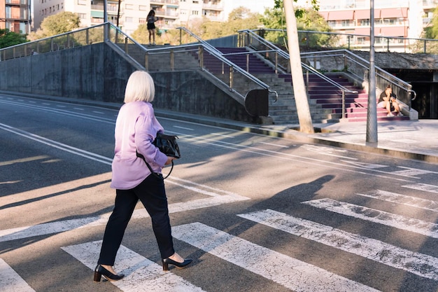 Foto donna anziana che attraversa una strada della città