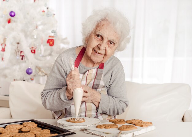 Senior woman decorating baked cookies