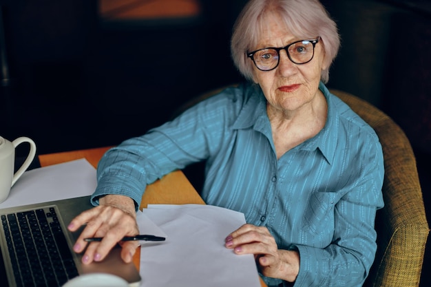 Senior woman documents work sheet of paper and pen Freelancer works unaltered