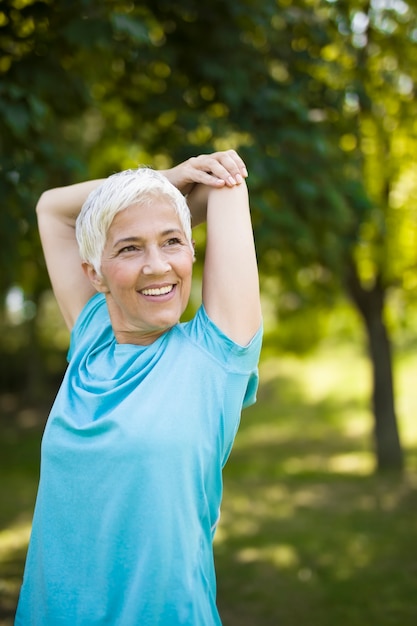 Senior woman doing exercise for stretching hand in the park